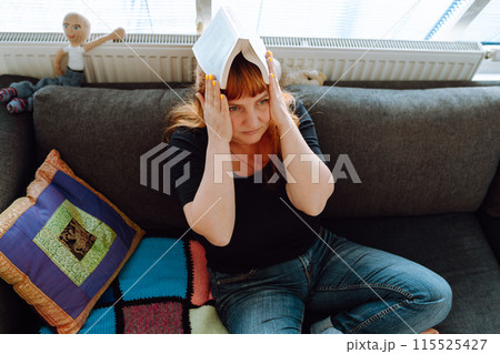 portrait middle-aged woman reading book while sitting on sofa 115525427