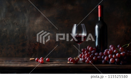 Bottle of red wine, glass of red wine, and grapes on a wooden table 115525580