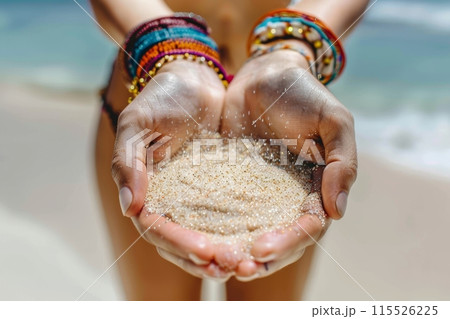 Close-up of a person's hands holding beach sand with bracelets, sea in the background. Hands Holding Sand at the Beach 115526225