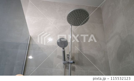 Fragment of a shower head against the background of brown ceramic tiles in the bathroom, close-up. Shower close-up without water. 115532123