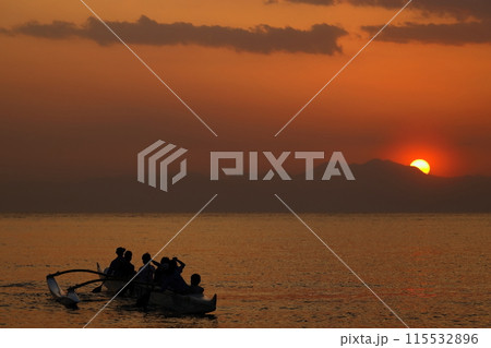 夕暮れの逗子海岸、オレンジ色に染まる海でボートの練習をする若者達のシルエット 夕暮れの逗子海岸、オレンジ色に染まる海でボートの練習をする若者達のシルエット 115532896