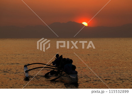 夕暮れの逗子海岸、オレンジ色に染まる海でボートの練習をする若者達のシルエット 115532899