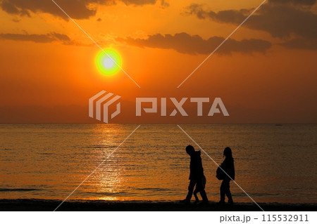 オレンジ色に染まる夕暮れの逗子海岸、波打ち際を散歩する家族のシルエット オレンジ色に染まる夕暮れの逗子海岸、波打ち際を散歩する家族のシルエット 115532911