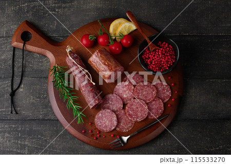 カッティングボードの上にのせた熟成サラミ　ピンクペッパーとローズマリーとプチトマトとレモン 115533270