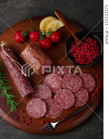 カッティングボードの上にのせた熟成サラミ　ピンクペッパーとローズマリーとプチトマトとレモン 115533271