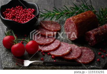 カッティングボードの上にのせた熟成サラミ　ピンクペッパーとローズマリーとプチトマト 115533291