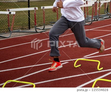 Runner running over yellow mini hurdles in practice 115534028