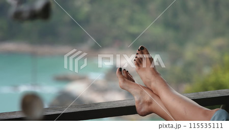 A person is seen resting comfortably with their feet propped up on a metal railing in an urban setting. 115535111