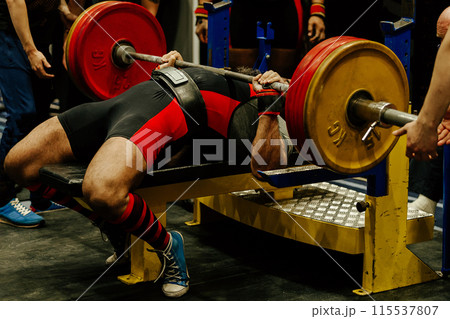 athlete perform bench press surrounded by assistants at powerlifting competition 115537807