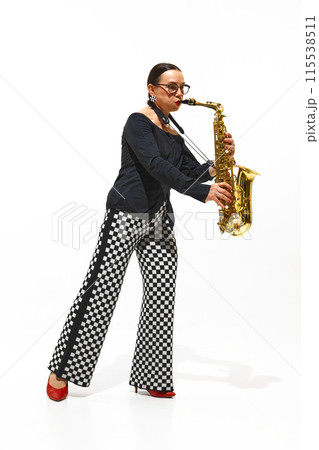 Full-length portrait of elegant senior woman, saxophonist in checkered pants performs intensely isolated on white background Full-length portrait of elegant senior woman, saxophonist in checkered pants performs intensely isolated on white background 115538511