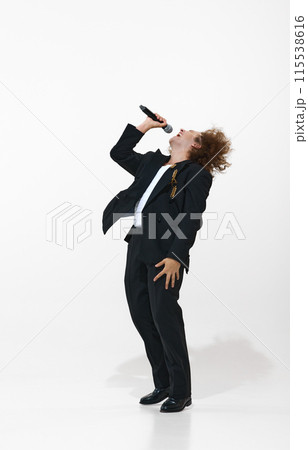 Young, curly-haired in blast suit emotionally singing in microphone isolated on white background. Energy and passion 115538616