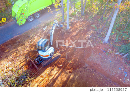 An uprooted tree is cleared for construction by tractor during construction 115538927