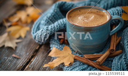 A Blue Mug of Cinnamon Coffee Resting on a Knit Blanket With Autumn Leaves 115539511