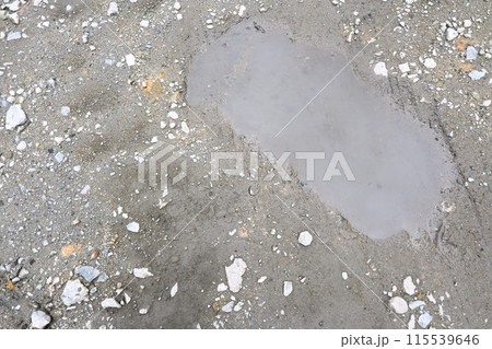 水たまりでぬかるんだ砂利の地面 水たまりでぬかるんだ砂利の地面 115539646