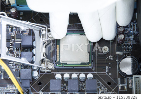 Top view of motherboard and technician about to insert CPU chip. 115539828