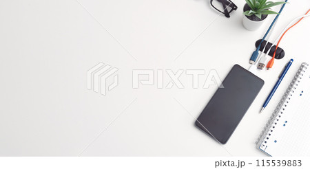 Office desktop with smartphone and accessories 115539883