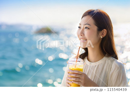 夏の海とトロピカルドリンクを持った若い女性 115540439