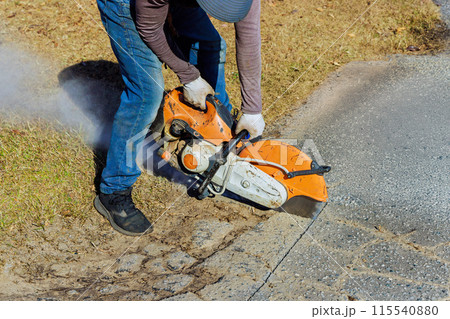 This construction worker uses diamond blade saw machine to cut damaged asphalt pavement This construction worker uses diamond blade saw machine to cut damaged asphalt pavement 115540880