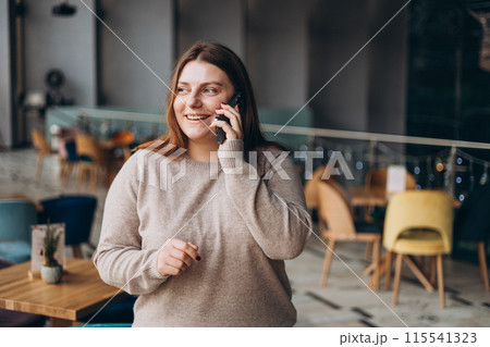 Young charming woman calling with cell telephone. Attractive 30s woman in casual wear spending free time talking on smartphone 115541323