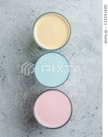 Trendy drinks: Blue, yellow and pink latte. Top view of hot butterfly pea or blue spirulina latte, yellow or gold turmeric latte and pink beetroot latte on gray cement background. Copy space for text Trendy drinks: Blue, yellow and pink latte. Top view of hot butterfly pea or blue spirulina latte, yellow or gold turmeric latte and pink beetroot latte on gray cement background. Copy space for text 115541680