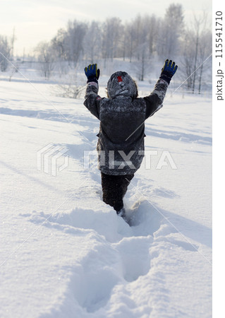 a child makes his way through deep snow. winter walks with the whole family. 115541710
