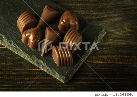 Dark chocolate candies on a serving board. Space for advertising on vintage black table 115541840