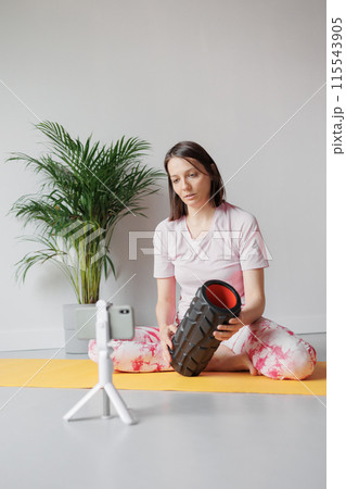 person works out in gym or home with foam roller. exercises for back, legs, hips, arms 115543905