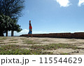Man Handstanding stone foundation along cliff shore next to shallow ocean 115544629