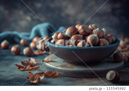 Hazelnuts in a ceramic bowl on a dark wooden background. 115545992