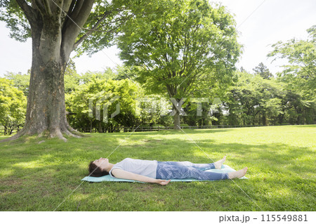 ヨガマットで寝る若い女性  アーシング、外ヨガイメージ 115549881