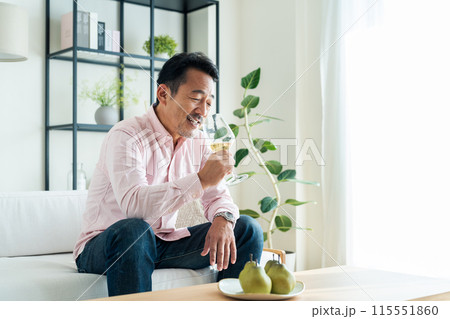 リビングで白ワインを飲むミドルの男性 115551860