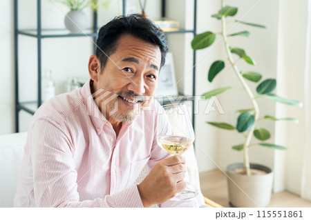 リビングで白ワインを飲むミドルの男性 115551861