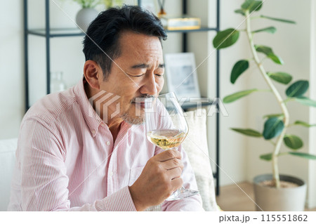 リビングで白ワインを飲むミドルの男性 115551862
