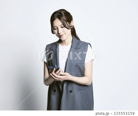白バックのスマホを持っているおしゃれな女性 白バックのスマホを持っているおしゃれな女性 115553159