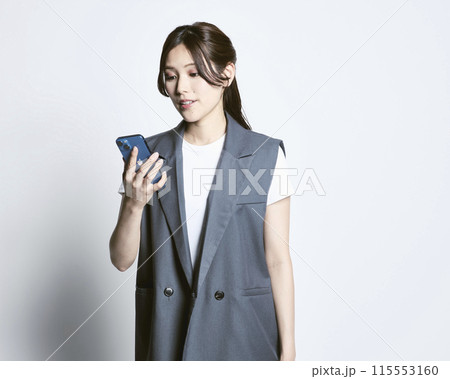 白バックのスマホを持っているおしゃれな女性 白バックのスマホを持っているおしゃれな女性 115553160