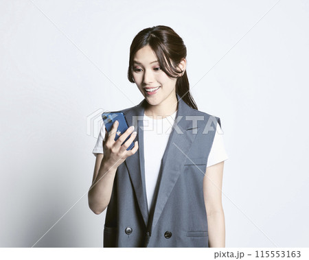 白バックのスマホを持っているおしゃれな女性 115553163