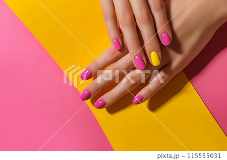 Female hands showcasing pastel stylish trendy manicure against a duotone yellow and pink background 115555031