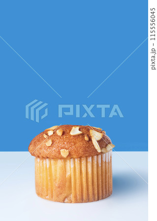 Almond muffin isolated on white table with blue background. Almond muffin isolated on white table with blue background. 115556045