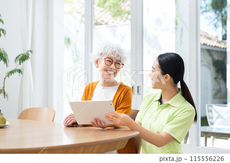 タブレットを使うシニアの女性と若い介護ヘルパー 115556226