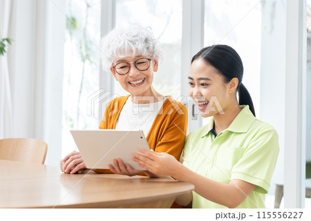 タブレットを使うシニアの女性と若い介護ヘルパー タブレットを使うシニアの女性と若い介護ヘルパー 115556227