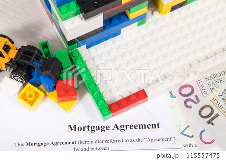 Unfinished house made of toy blocks, miniature excavator, polish money, mortgage agreement form. 115557475