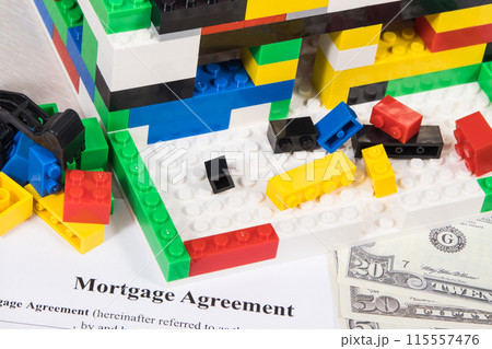 House under construction made of toy blocks, dollars, mortgage agreement form 115557476