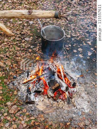 Black old pot with cooked food near the fire. 115557611
