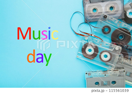 Inscription music day with old colorful cassettes on a blue background. Music day Inscription music day with old colorful cassettes on a blue background. Music day 115561039
