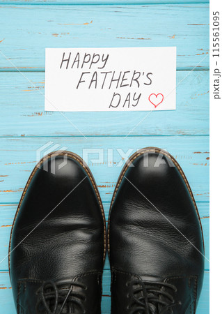 Happy Fathers Day message and black shoes on blue wooden background. Happy Fathers Day message and black shoes on blue wooden background. 115561095