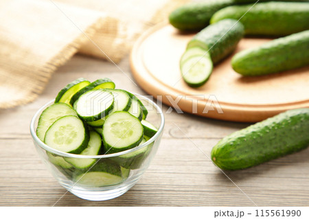 Fresh cucumber slices in bowl on grey wooden background. Fresh cucumber slices in bowl on grey wooden background. 115561990