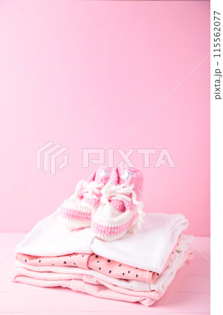 Baby clothes with booties on pink background with copy space 115562077