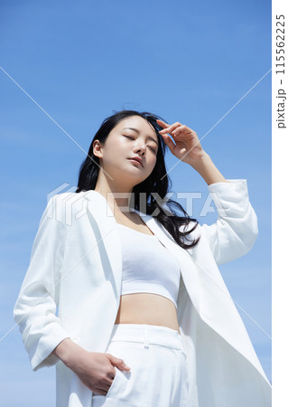 空背景で撮影をした白いジャケットを着た若い女性のポートレート 空背景で撮影をした白いジャケットを着た若い女性のポートレート 115562225