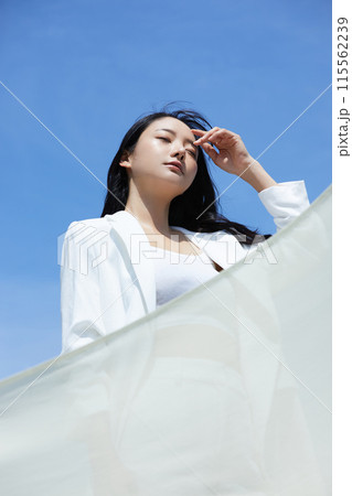 空背景で撮影をした白いジャケットを着た若い女性のポートレート 空背景で撮影をした白いジャケットを着た若い女性のポートレート 115562239