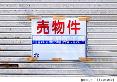 シャッターに貼られた売物件の看板 115563634